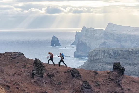 Zwei Wanderer mit Wanderucksäcken auf einem Vulkangrat hoch über dem Meer.